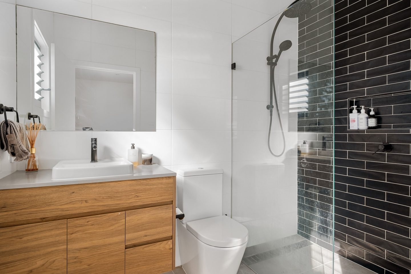 Baño con lavamanos sobre mueble de madera y ducha de vidrio