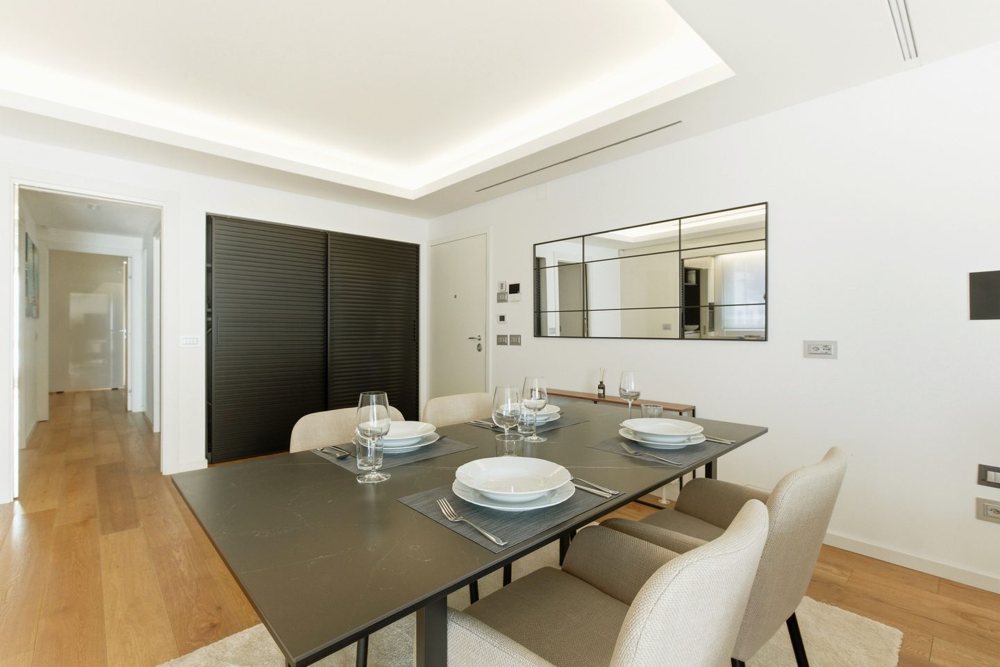 Comedor con mesa para seis, sillas claras y luz indirecta en el techo